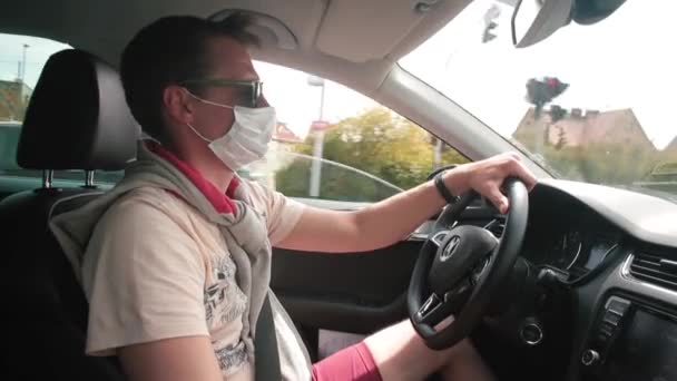 Le conducteur de voiture masqué contrôle le véhicule au volant. Il utilise le téléphone dans les mains, — Video