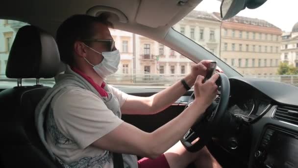 Маска людина використовує телефон під час водіння автомобіля Він отримує листування — стокове відео