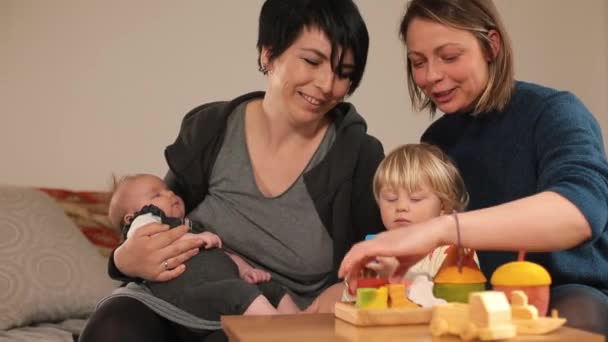Two women talk children when they meet. Discussing an eco-friendly wooden toy. — Stock Video