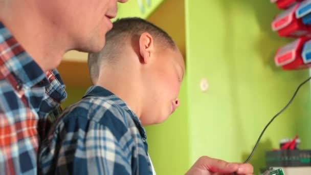 Pa en zoon richten zich op het maken van een elektrisch apparaat Hot fixing elektrische onderdelen — Stockvideo