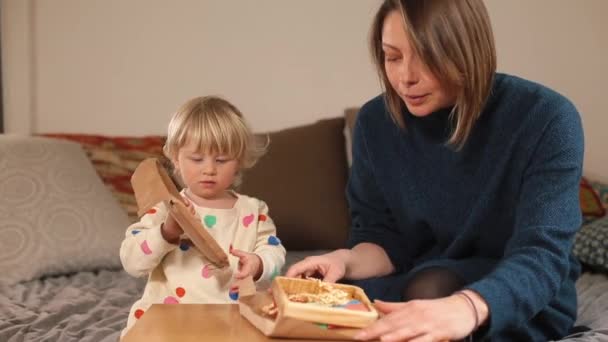 Criança abre presente na frente mãe Ela desdobra rolagem, toca com as mãos — Vídeo de Stock