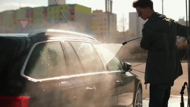 Mann wäscht Türen Fenster Autowasser Es wäscht trockenen Schmutz mit Wasserdruck weg — Stockvideo