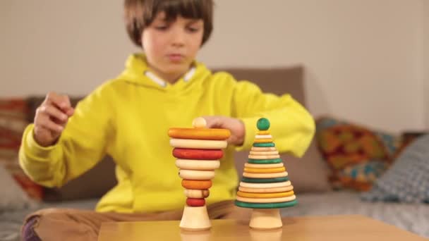 Teenager in gelben Kleidern macht magische Bewegungen mit den Händen Holzpyramiden Spielzeug — Stockvideo