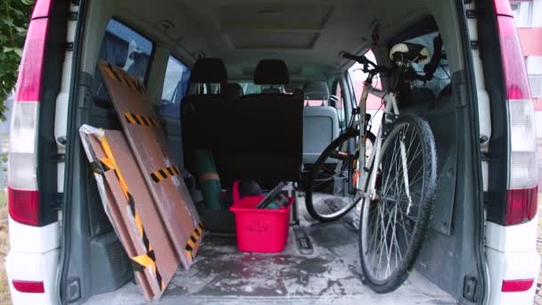 Un uomo prende una scatola rossa con le cose fuori dal minivan con le mani. — Video Stock