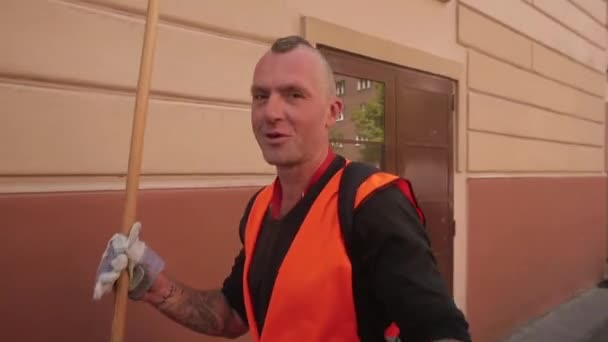 Ένας άντρας με πορτοκαλί γιλέκο και γάντια μιλάει εν κινήσει σε δρόμο της πόλης.. — Αρχείο Βίντεο