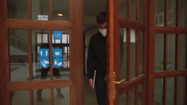 De gemaskerde man komt de deur uit. Verplaatsen van een werknemer in de werkruimte. — Stockvideo