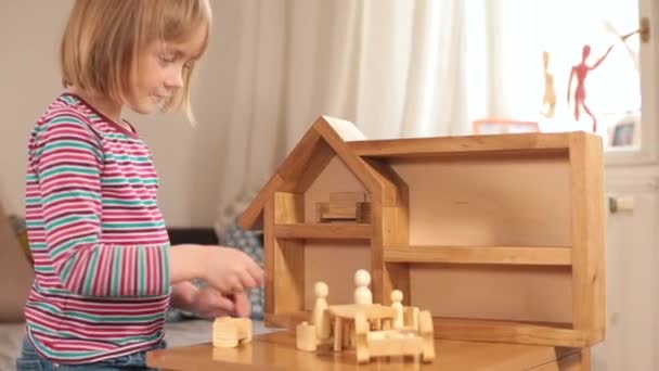 3.女孩在桌子上玩木制玩具。她把雕像放在木屋里. — 图库视频影像