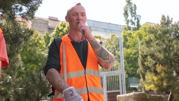 Un employé en gilet orange fume un singe. Il libère de la vapeur dans la lumière. — Video