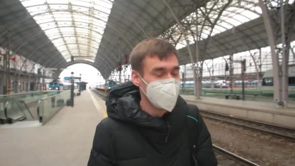 Maskierter Mann am Bahnhof. Er bewegt sich durch den Bahnhof und wartet auf den Zug. — Stockvideo