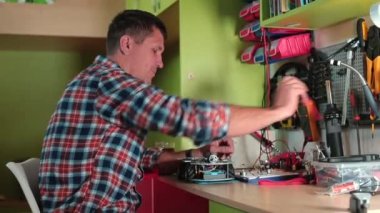 Adam vidaları tornavida sehpasıyla söküyor. Atölyede çalışıyor, oyuncak araba yapıyor.