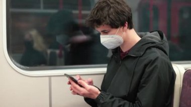 Maskeli yolcu telefon toplu taşıma mobil internet bilet uygulaması kullanıyor