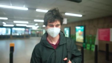 Maskeli adam toplu taşıma istasyonunda yürüyor. Eksi seviye yürüyen merdivenden iniyor.