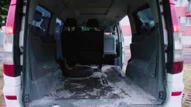 Açık bagajlı bir minivan evin yakınındaki otoparktan ayrılıyor.
