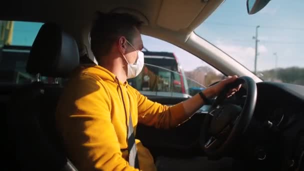 Man met masker rijdt auto op de weg in de stad. Hij bestuurt bewegingsvoertuigen met handen. — Stockvideo