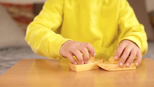 Kleine Jungenhände spielen mit Holzbasteleien auf dem Tisch. Simulierter Kampf. — Stockvideo