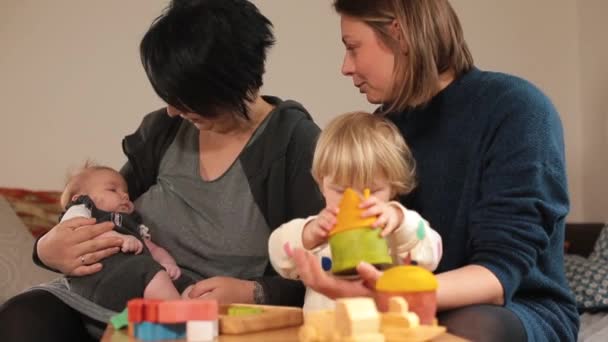 一个家庭妇女和一个带着玩具的女婴玩耍。孩子在她怀里. — 图库视频影像