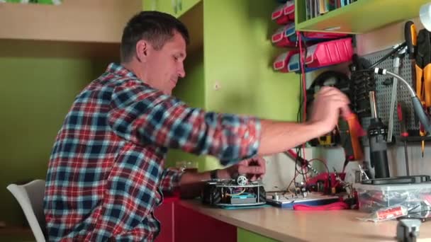 Mann schraubt Schraube mit Schraubtisch ab Er arbeitet in der Werkstatt, baut Spielzeugautos — Stockvideo