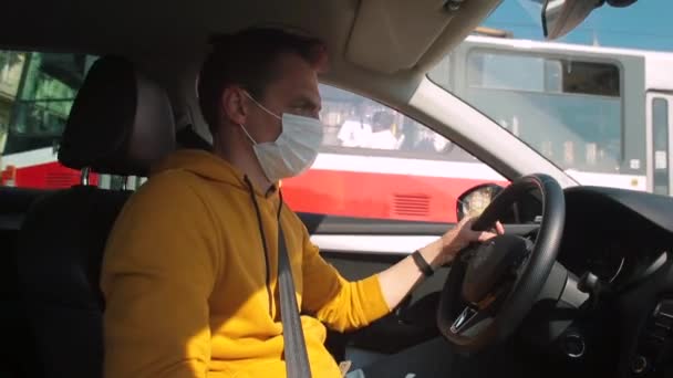 El taxista enmascarado conduce un coche en la ciudad. Mantiene sus manos en el volante, gira el coche. — Vídeo de stock