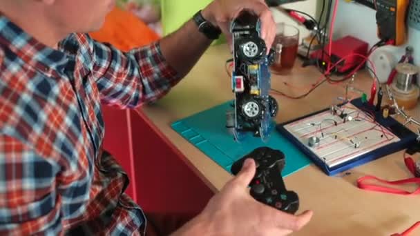 Man beweegt wielen speelgoed met behulp van draadloze controller Reparatie onderhoud digitaal speelgoed — Stockvideo