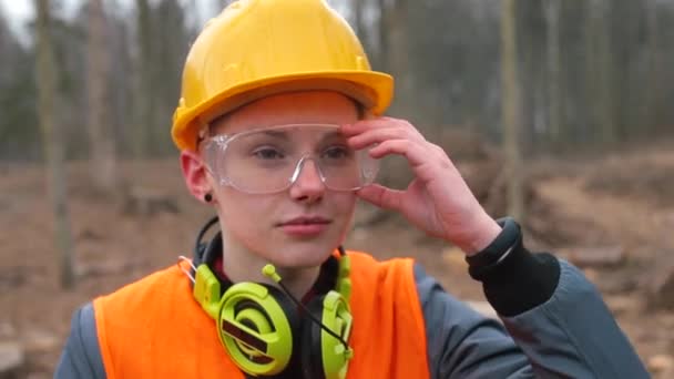 Trabalhador de retrato em capacete e óculos. Auscultadores à volta do pescoço. — Vídeo de Stock