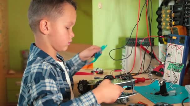Boy workshop unscrews screw on toy car. He turns hand, remanufactures wheel — Stock Video