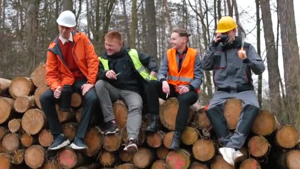 Um grupo de trabalhadores sentados em troncos de árvores. Levam metade do resto do trabalho.. — Vídeo de Stock