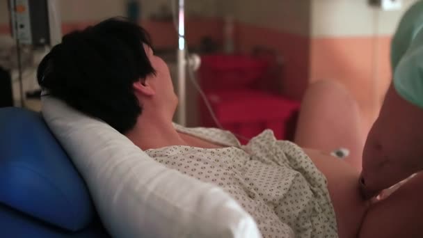 Женщина лежит на кровати во время родов. Она дышит, расслабляется между схватками — стоковое видео