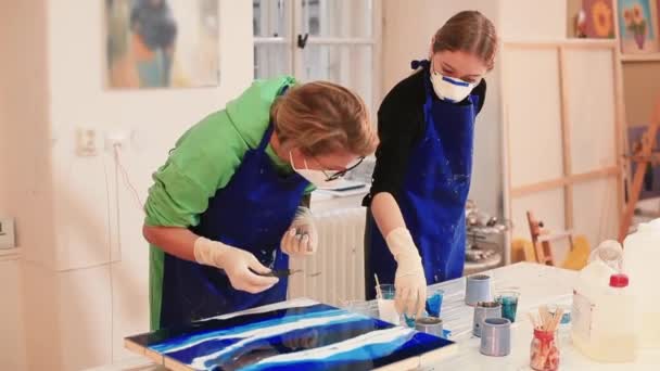 Zwei Künstler schaffen ein Kunstwerk. Inspirierter Künstler gießt Farbe auf die Malerei — Stockvideo