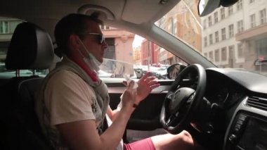 Adam ellerini özel peçetelerle yıkıyor. Kiralık arabada el ve ayak parmaklarını siliyor.