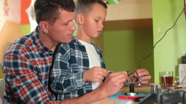 Vater und Sohn konzentrieren sich auf die Arbeit mit dem Lötkolben. Sie stellen eine Verbindung her. — Stockvideo