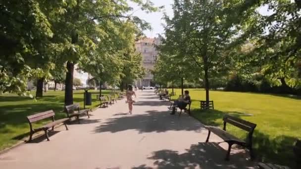 Kamera bevægelse vej i byens park mand sidder bænk. sommerdag i byen. – Stock-video