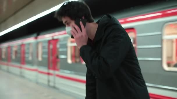 Masked man speaks on phone while train moves. He receives urgent message voice — Stock Video