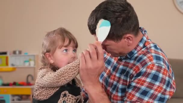 Η κόρη χτενίζει τα μαλλιά της. Κάνει τον μπαμπά να φροντίζει τον εαυτό του. — Αρχείο Βίντεο