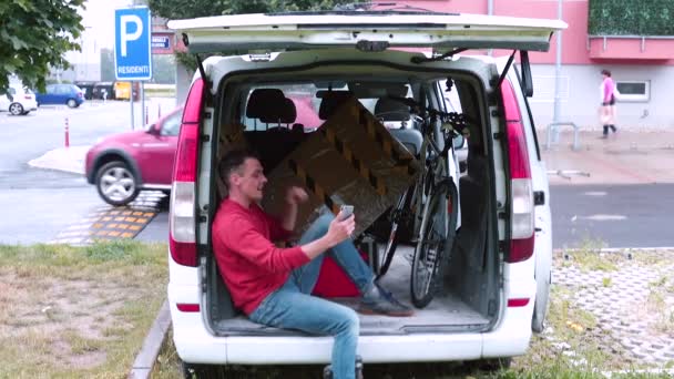 A man is talking on video call using phone in trunk car. Delivery of things. — Stock Video
