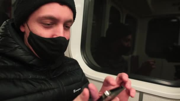 Ankomst station, stopp maskerad man sitter vid tågfönstret med hjälp av telefon — Stockvideo