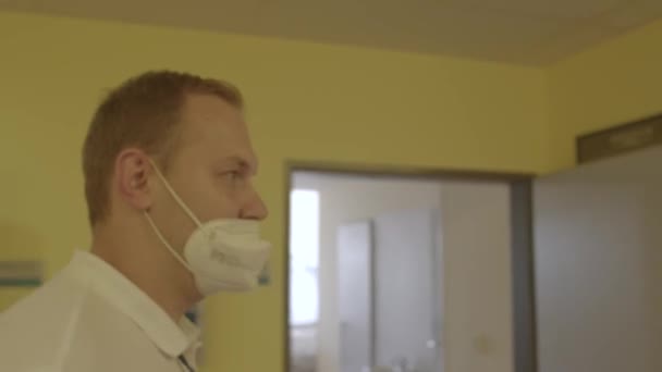 Uomo mascherato si muove lungo il corridoio ospedale guarda avanti concentrarsi mente prima di lavorare — Video Stock