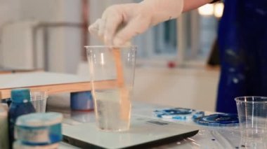 Temiz sıvıyı cam ölçekte karıştırıyorum. Boyamadan önce epoksi malzemeyi hazırlayın..