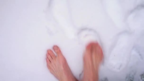 Un homme aux pieds nus marche sur la neige d'herbe. Durcissement du corps en hiver. — Video