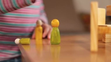Masanın üzerinde yakın plan ahşap biblolar. Küçük mutfak eşyalarıyla oynayan çocuk elleri