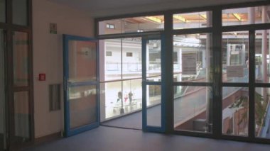 İşçi kırmızı elbiseleri yürüme koridoru Cam kapılar Maske takmaya saygı