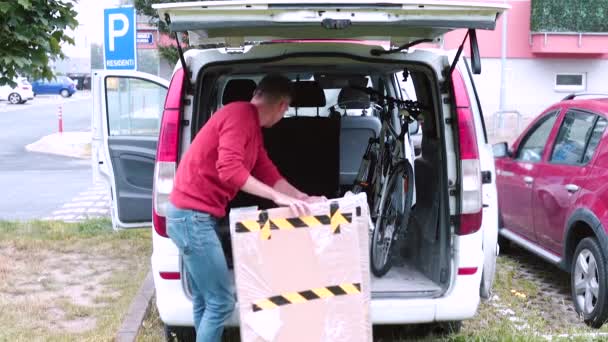 Mann lädt Ladung in den Kofferraum des Autos Er legt Gegenstände in den Minivan. — Stockvideo