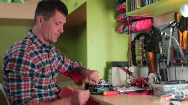 Adam bir elektrikli alet masasını tamir ediyor, tornavida tornavidaya dönüyor.
