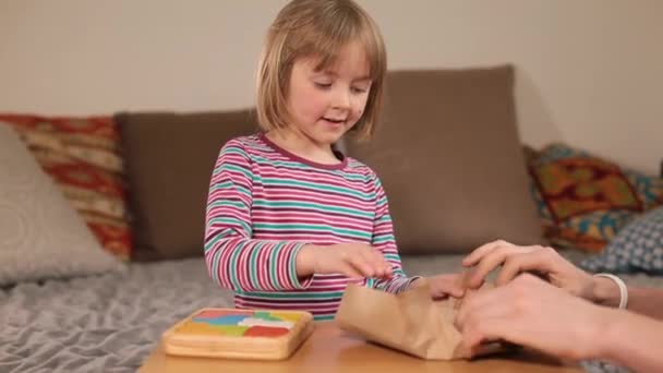 Rozpakowywanie nowej zabawki na stole dziewczyna otwiera pakiet z jej rąk i dotyka przedmiotów — Wideo stockowe