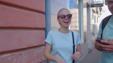 Neşeli bir kadın bir erkeği bekliyor. Taksi çağırır. Gözlerde gözlük..