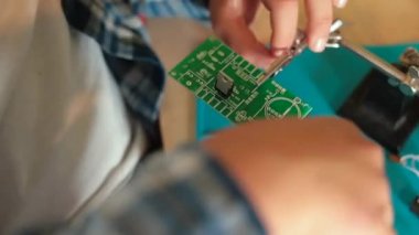 Bir genç elektronik pano yapıyor. Parçaları elleriyle tamir ediyor.. 