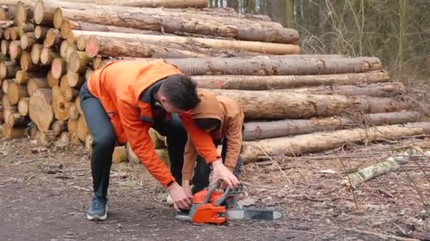 Молодий менеджер вчить дитину використовувати бензопилу Лісова школа в лісозаготівлях . — стокове відео