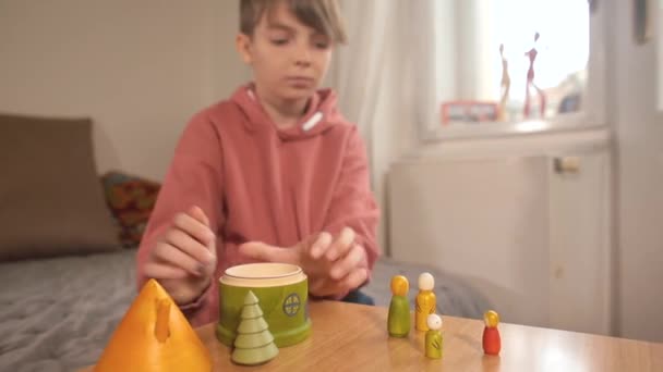 Um adolescente talentoso reúne figuras de madeira. Brinquedo ecológico em casa. — Vídeo de Stock