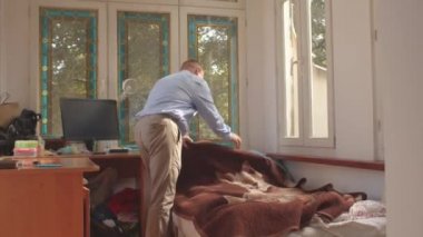 Adam odada yatak yapıyor. Seyreldikten sonra sabah işi. Odayı temizliyorum..