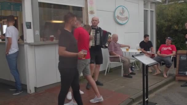 Muž hraje na akordeon u vchodu do kavárny. Zvyšování nálady návštěvníků — Stock video