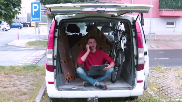 Ein Mann, der im Kofferraum eines Autos sitzt, benutzt das Telefon. Lieferung Dinge neue Adresse. — Stockvideo